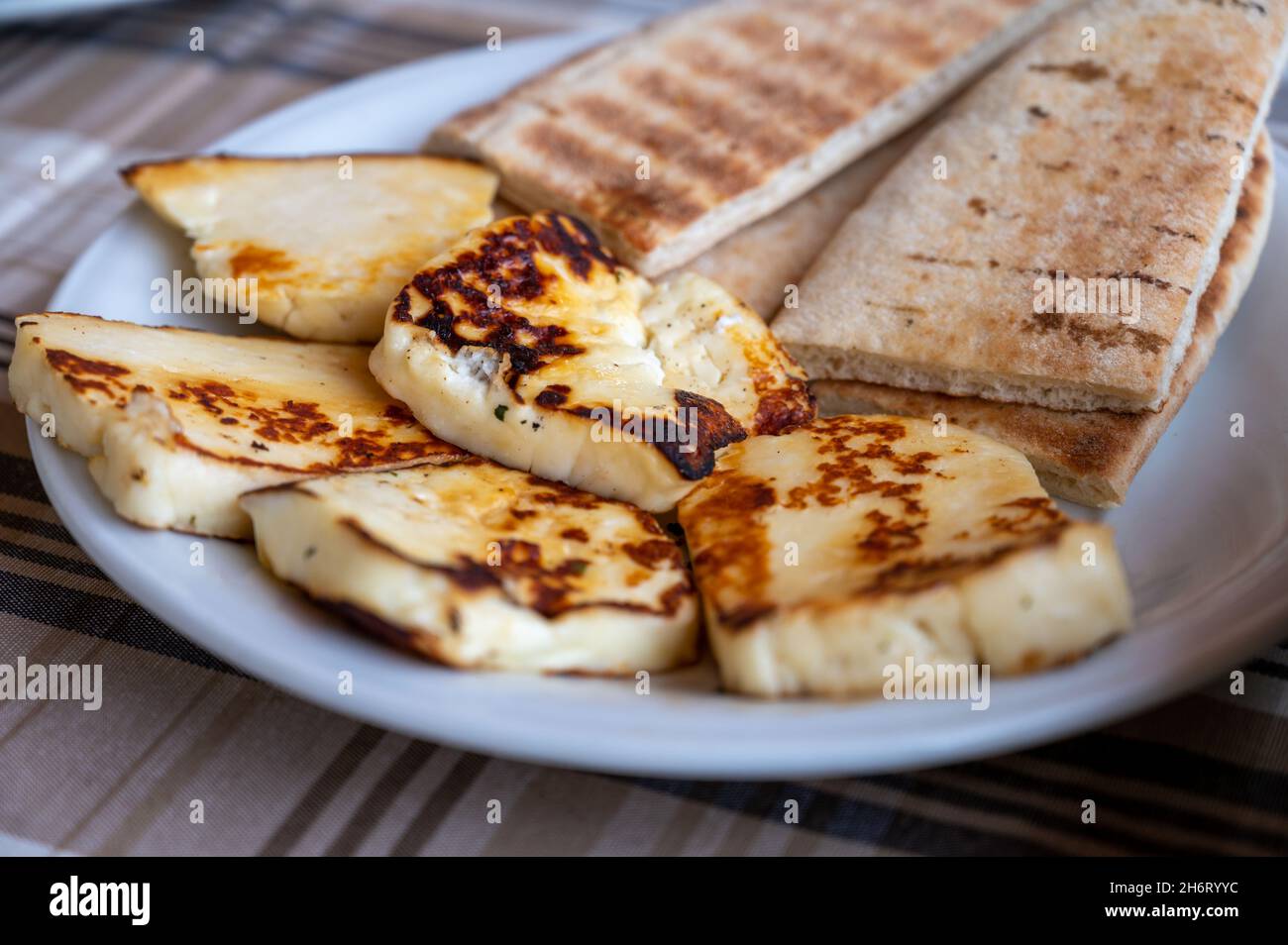 Traditional roasted or grilled halloumi cheese from Cyprus served hot with flat greek bread Stock Photo