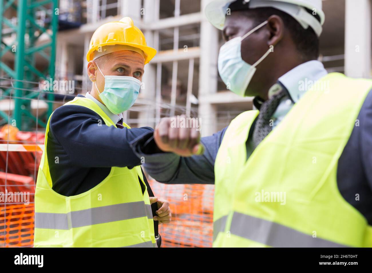 Buildres Mask Builders in masks greeting each other by elbow bump Stock Photo - Alamy