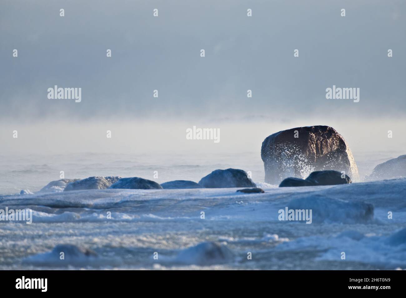Ice covered rock by the Baltic Sea that about to freeze over with water splashing against the rocks in Helsinki, Finland on 14 January 2021. Stock Photo