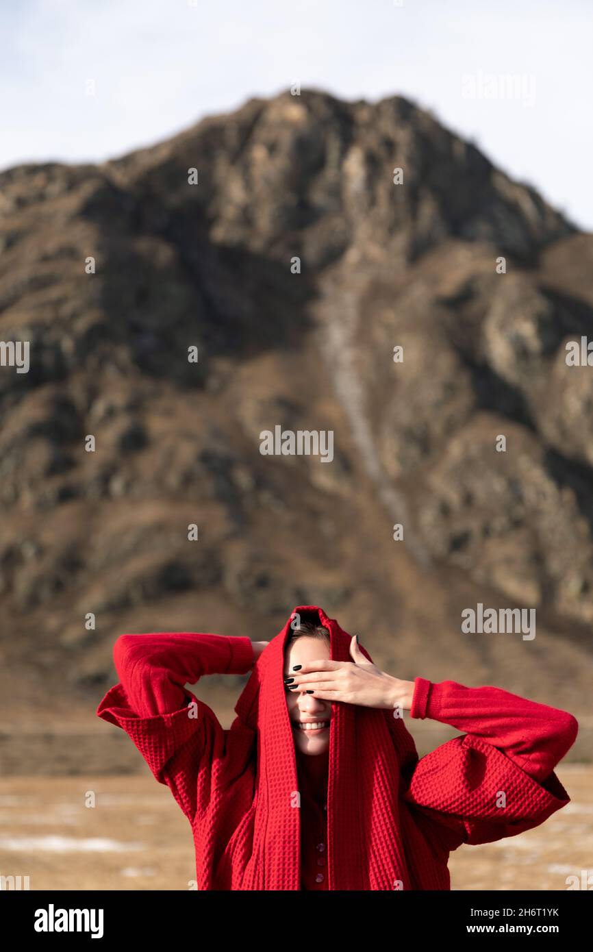 Woman smiling in red coat closed hand eyes Stock Photo
