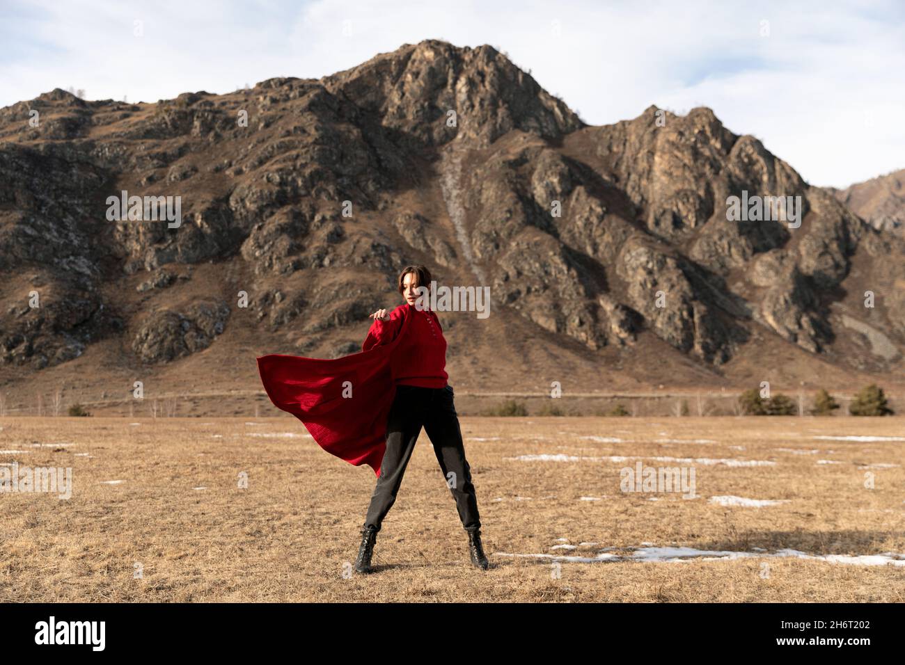 Woman in red coat dancing next to the mountain Stock Photo