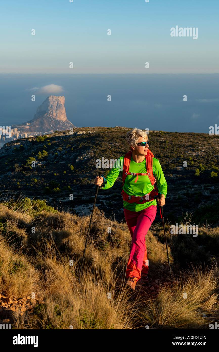 Young female hiking on Oltá mountain over mediterranean sea, Calpe, Alicante province, Spain Stock Photo