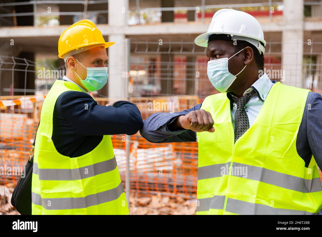Buildres Mask Builders in masks greeting each other by elbow bump Stock Photo - Alamy