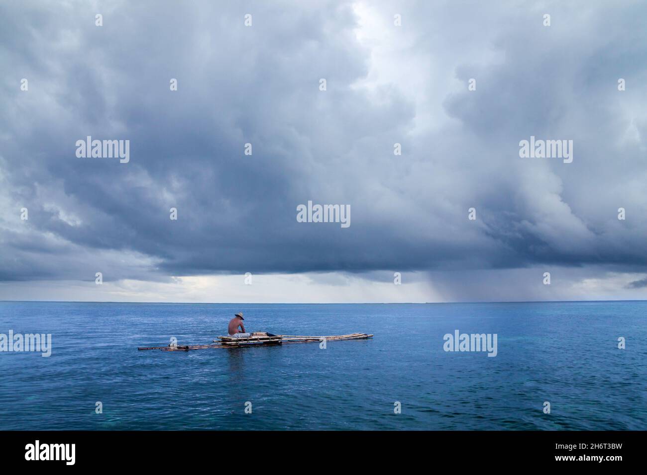 A rain cell passes by offshore of a local fisherman on a handmade ...