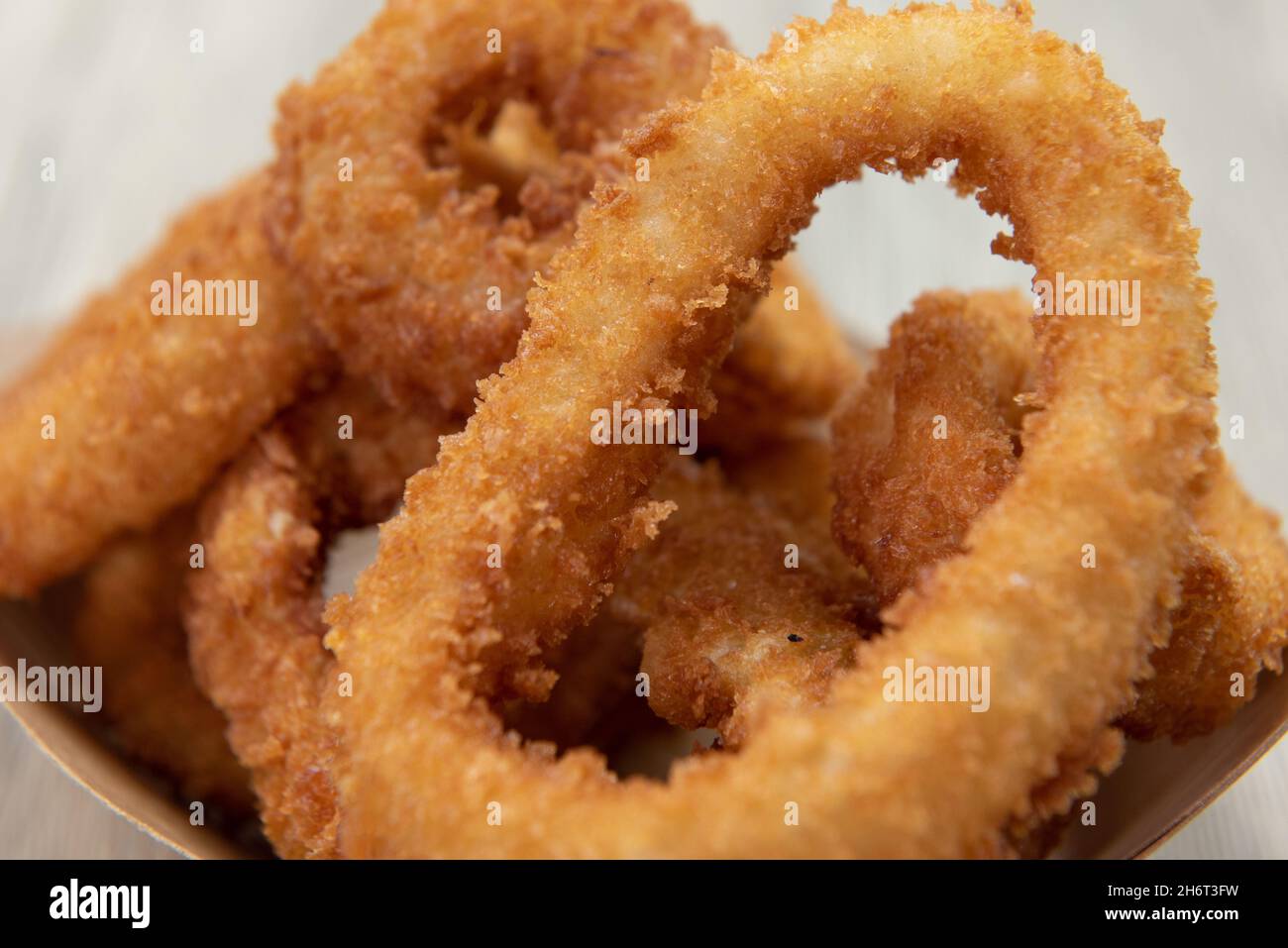 Close up of texture of crispy side order of onion rings contained in a cardboard boat to eat on the go. Stock Photo