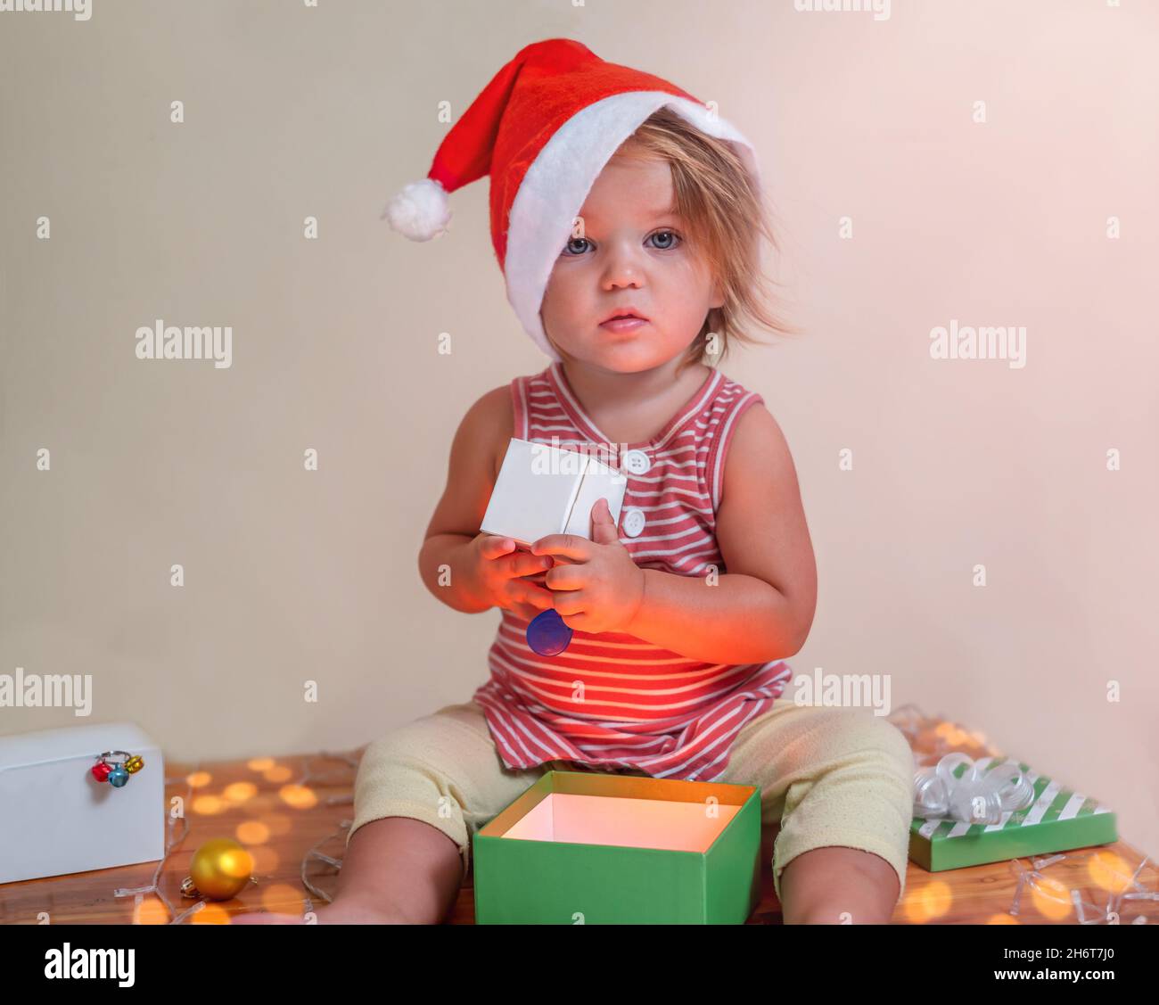 Surprised and confused child in a Santa hat and with gifts Stock Photo