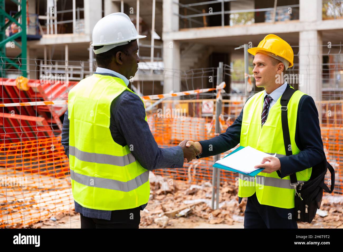Engineers shaking hands on construction site Stock Photo