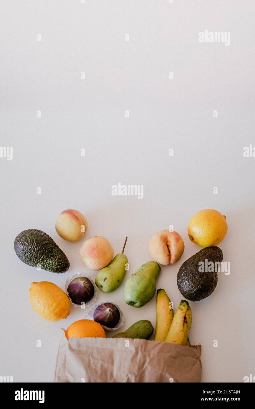 A variety of fruits in a crafted paper bag are lying on the table