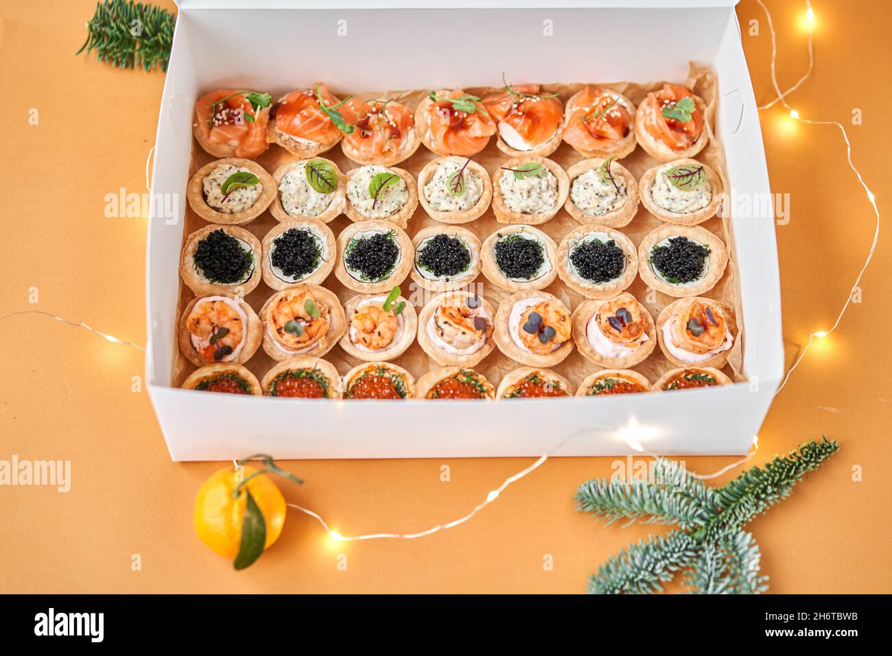 Black and Red caviar with butter in tartlets, crispy shrimps with lemon in sauce in take way box. Menu food for delivery in the Coronavirus Pandemic. Stock Photo