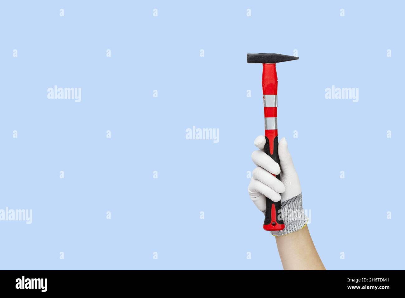 Gloved hands holding hammer construction tools. Work tools on blue background Stock Photo
