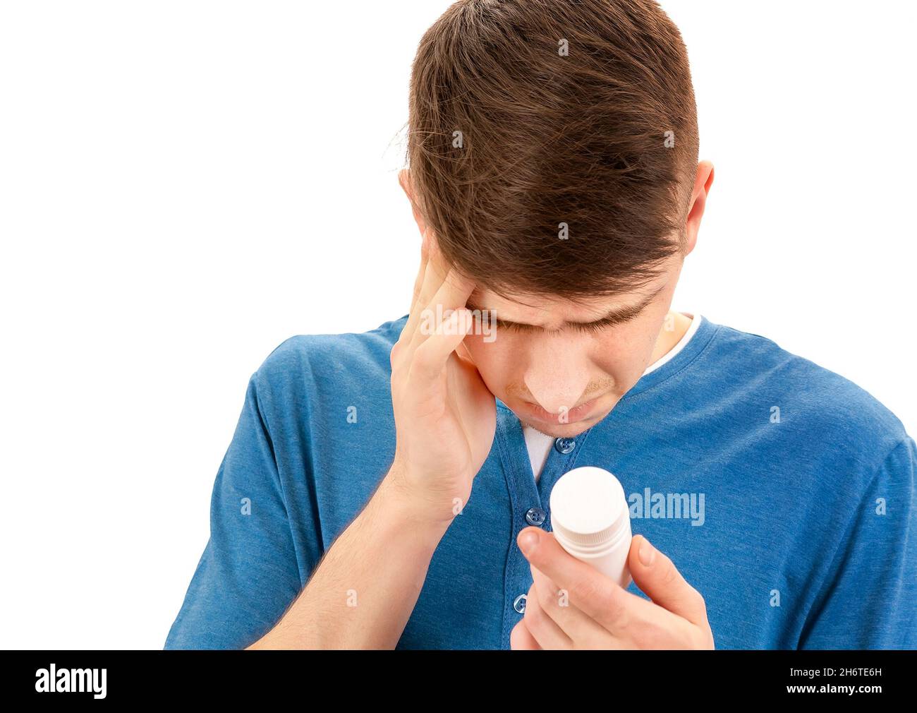 Young Man with the Bottle of the Pills feels a Side Effect on the White Background closeup Stock Photo