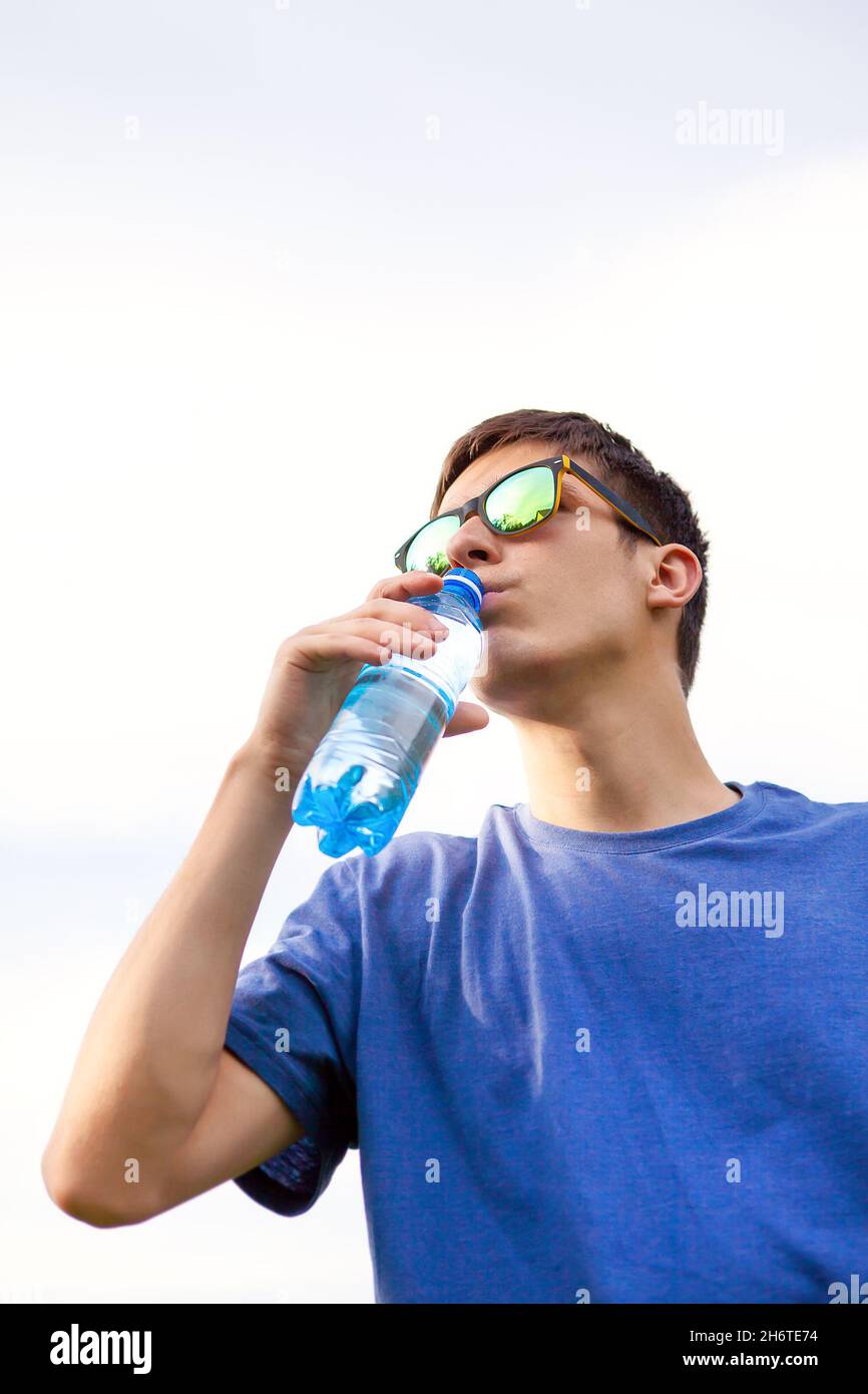 Young Man drink a Pure Water on the Sky Background Stock Photo