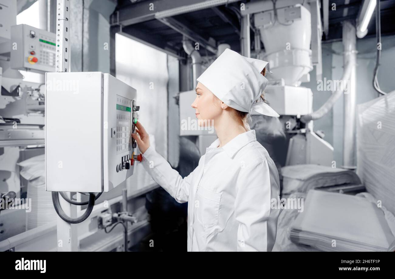 Factory engineer woman operating machine control panel in mill flour