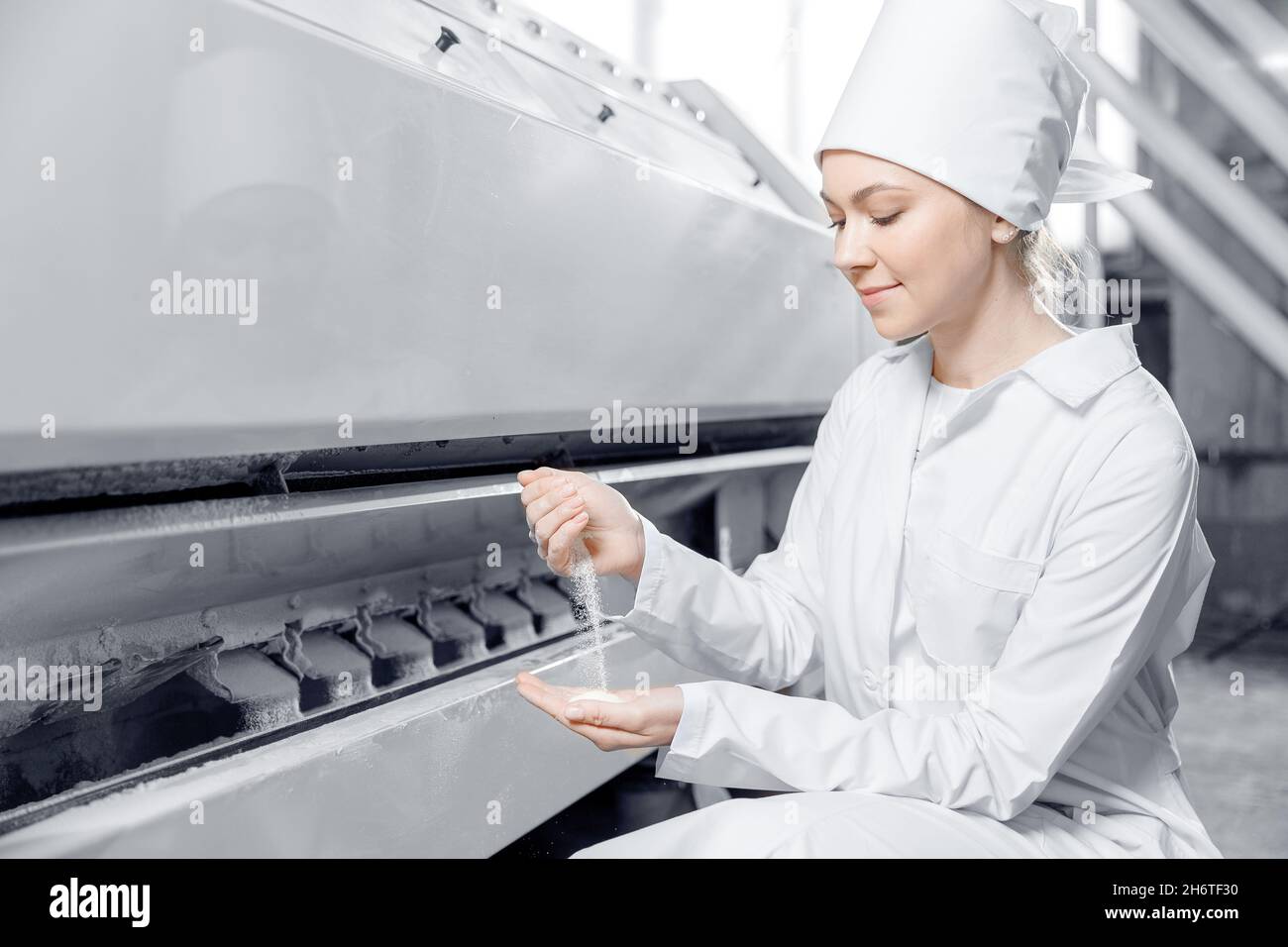 Woman operator checks quality of finished food products. Modern electrical mill machinery for
