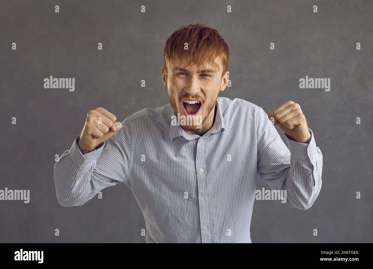 Shouting angry man raging quarreling studio headshot portrait on grey background Stock Photo