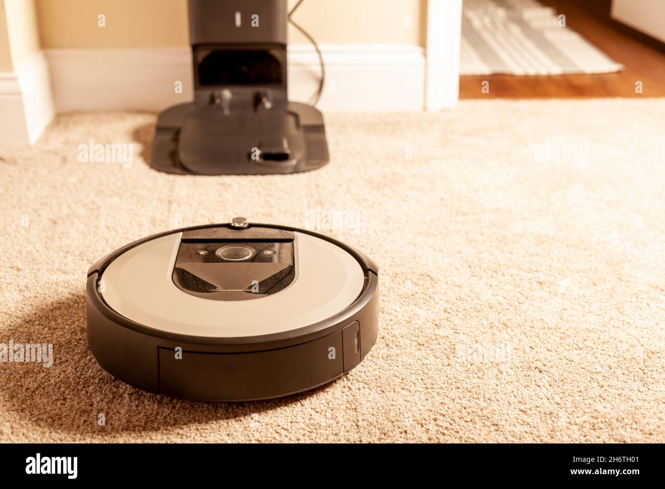 Close up generic image for robot vacuum cleaner. This unit is operating on carpetted floor and heading towards its base station for charging and empty Stock Photo