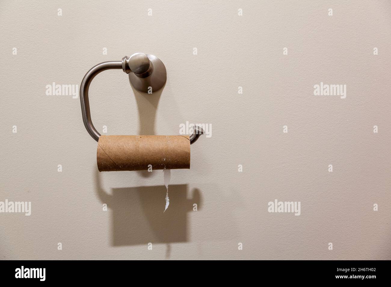 Concept image showing a toilet paper hanger with an empty toilet paper roll hanging on it. Useful image for shortage related to disturbed suply chain Stock Photo