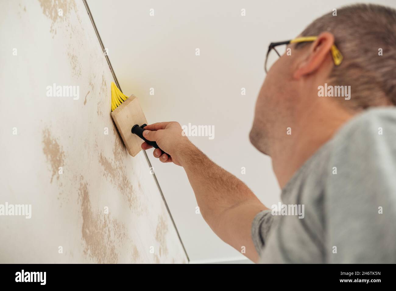 A Man Applies Wallpaper Glue With Brush For Wallpapering Repair Of