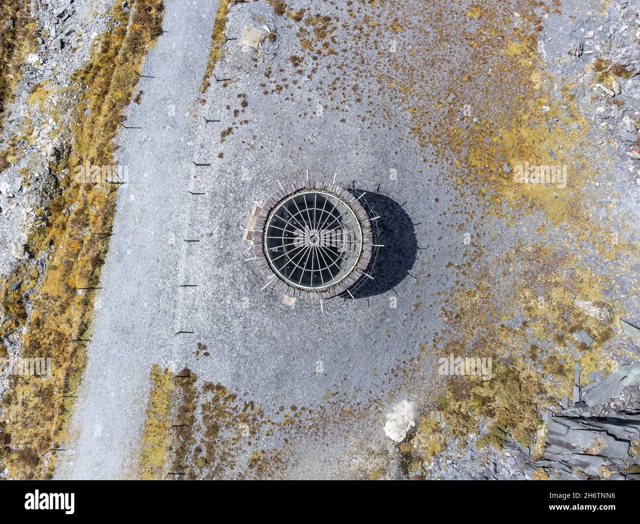 Old abandoned coal pit mine shaft. End of the mining industry capped to make safe at slate quarry. Aerial view from drone of industrial spooky dark Stock Photo