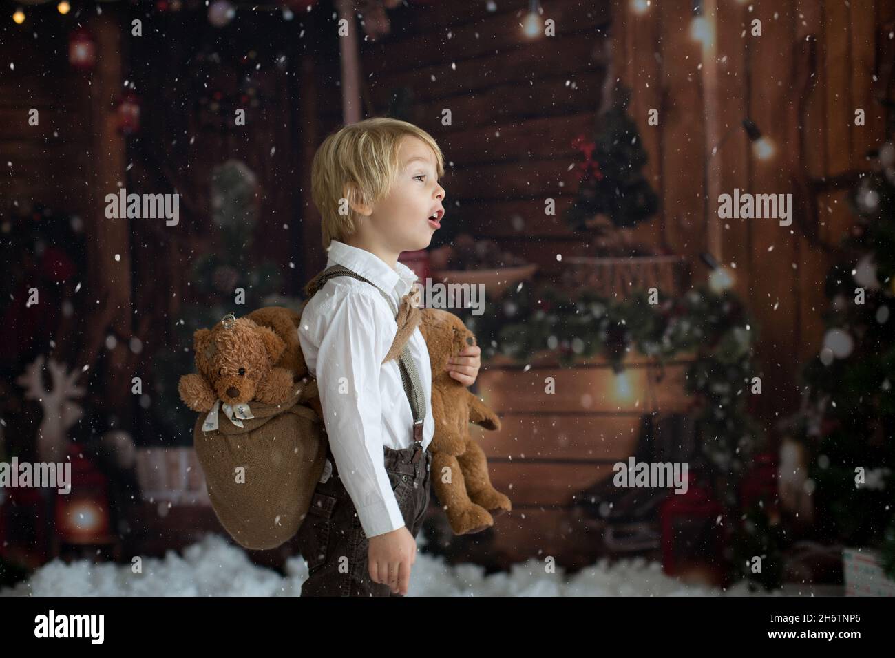 Cute fashion toddler boy, playing in the snow with teddy bear in front ...