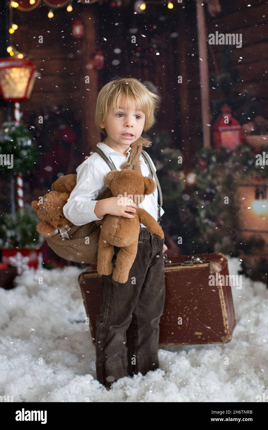 Cute fashion toddler boy, playing in the snow with teddy bear in front ...