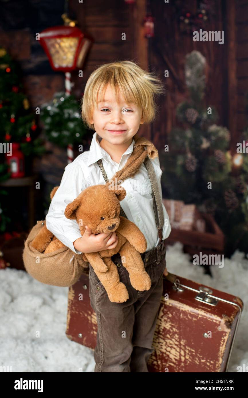 Cute fashion toddler boy, playing in the snow with teddy bear in front ...