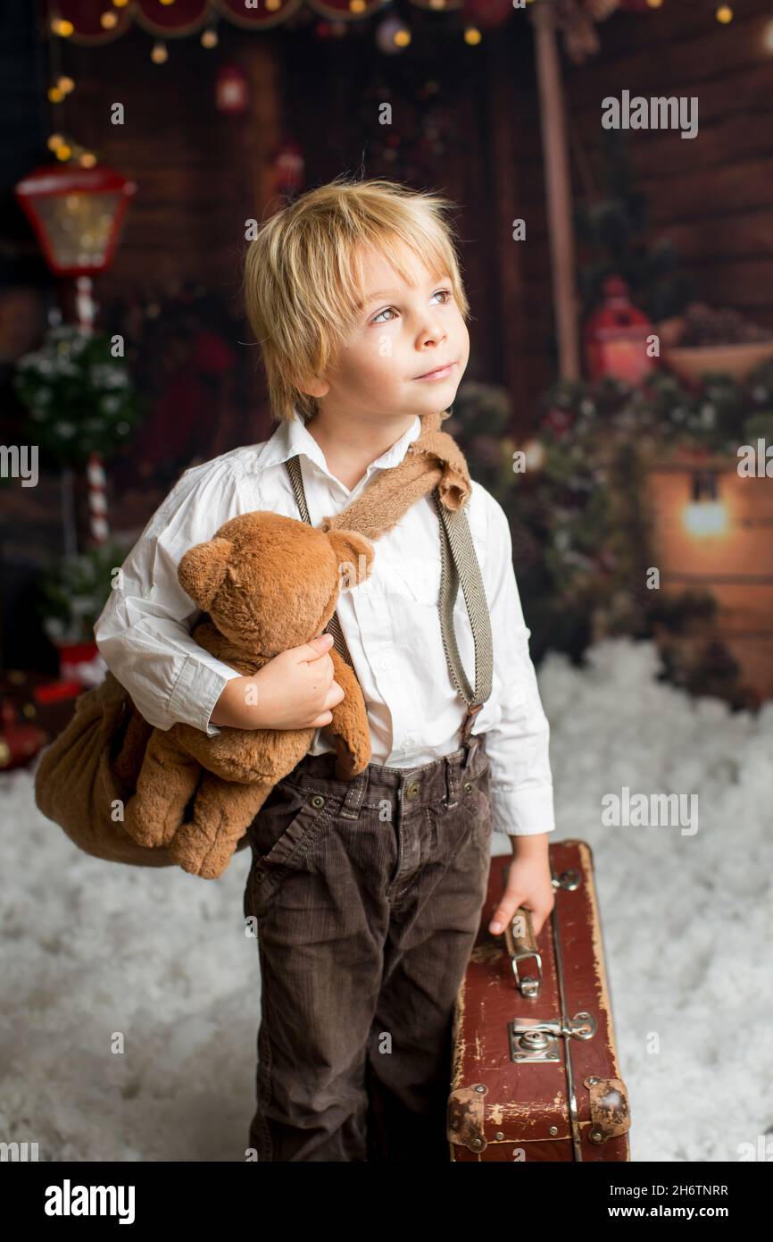 Cute fashion toddler boy, playing in the snow with teddy bear in front ...