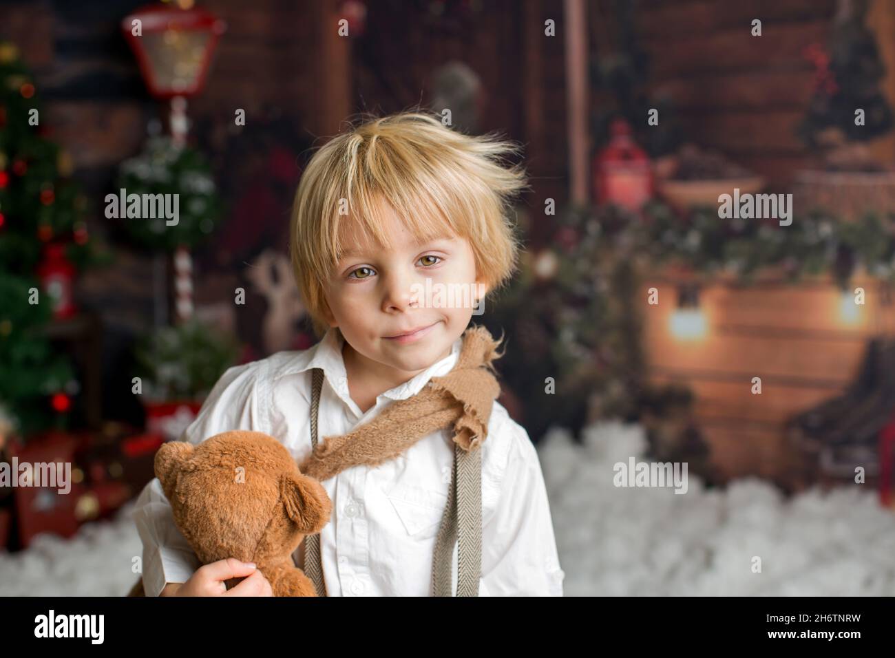 Cute fashion toddler boy, playing in the snow with teddy bear in front ...