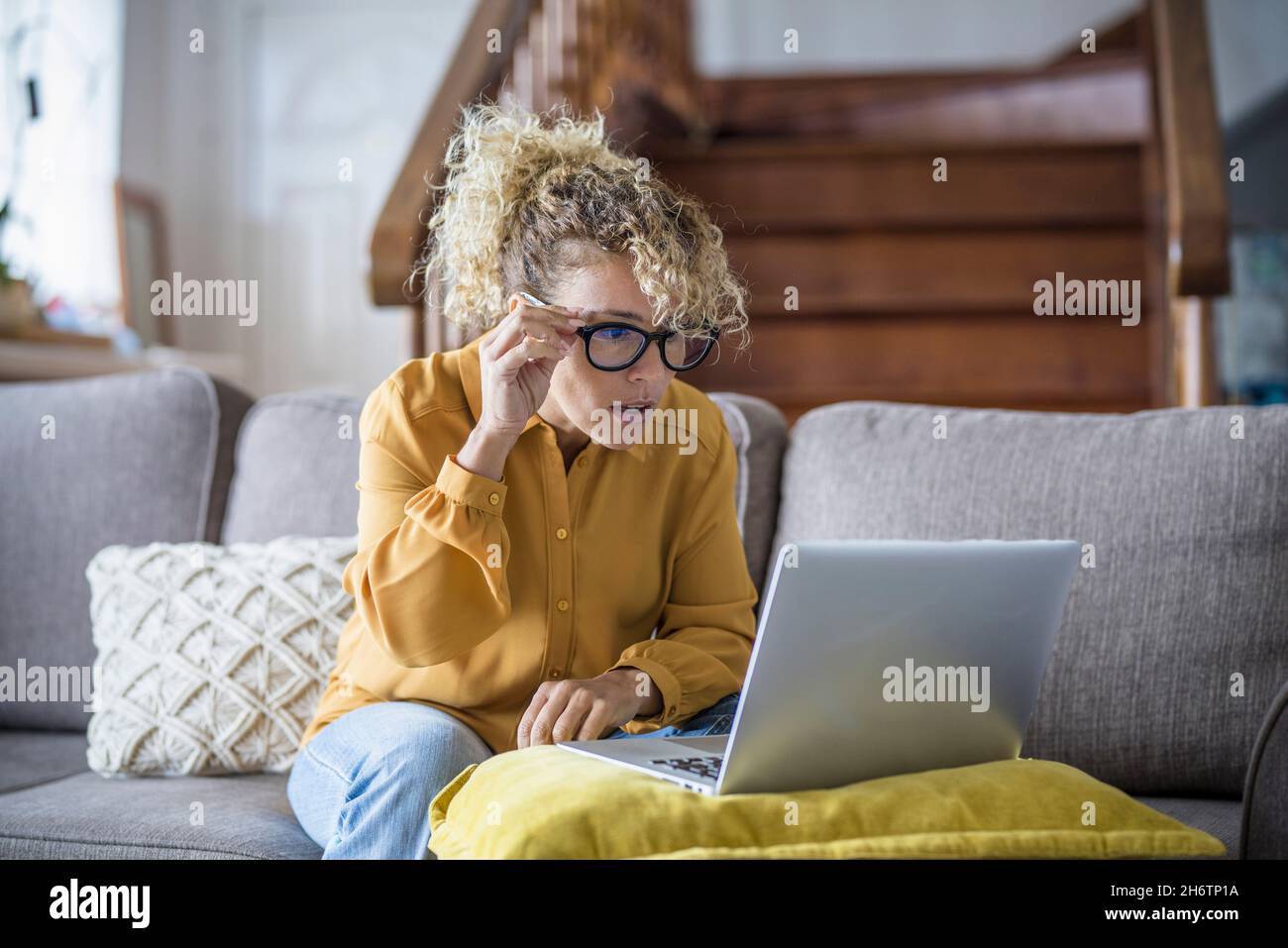 Surprised and worried adult woman reading bad notification on laptop computer at home in online work activity. Security and shopping modern concept pe Stock Photo