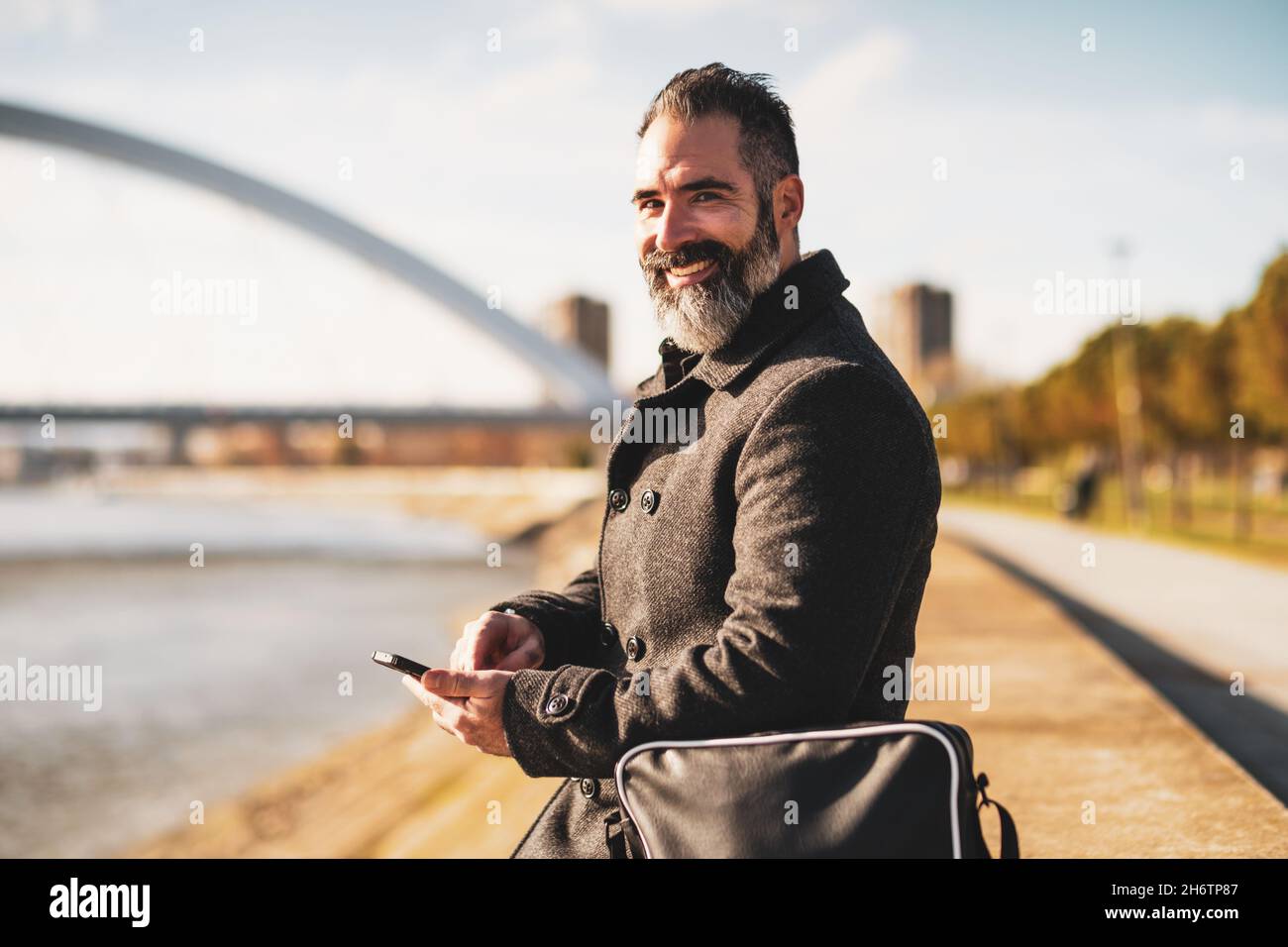 Businessman is sitting outdoor in the city and using smartphone. Stock Photo