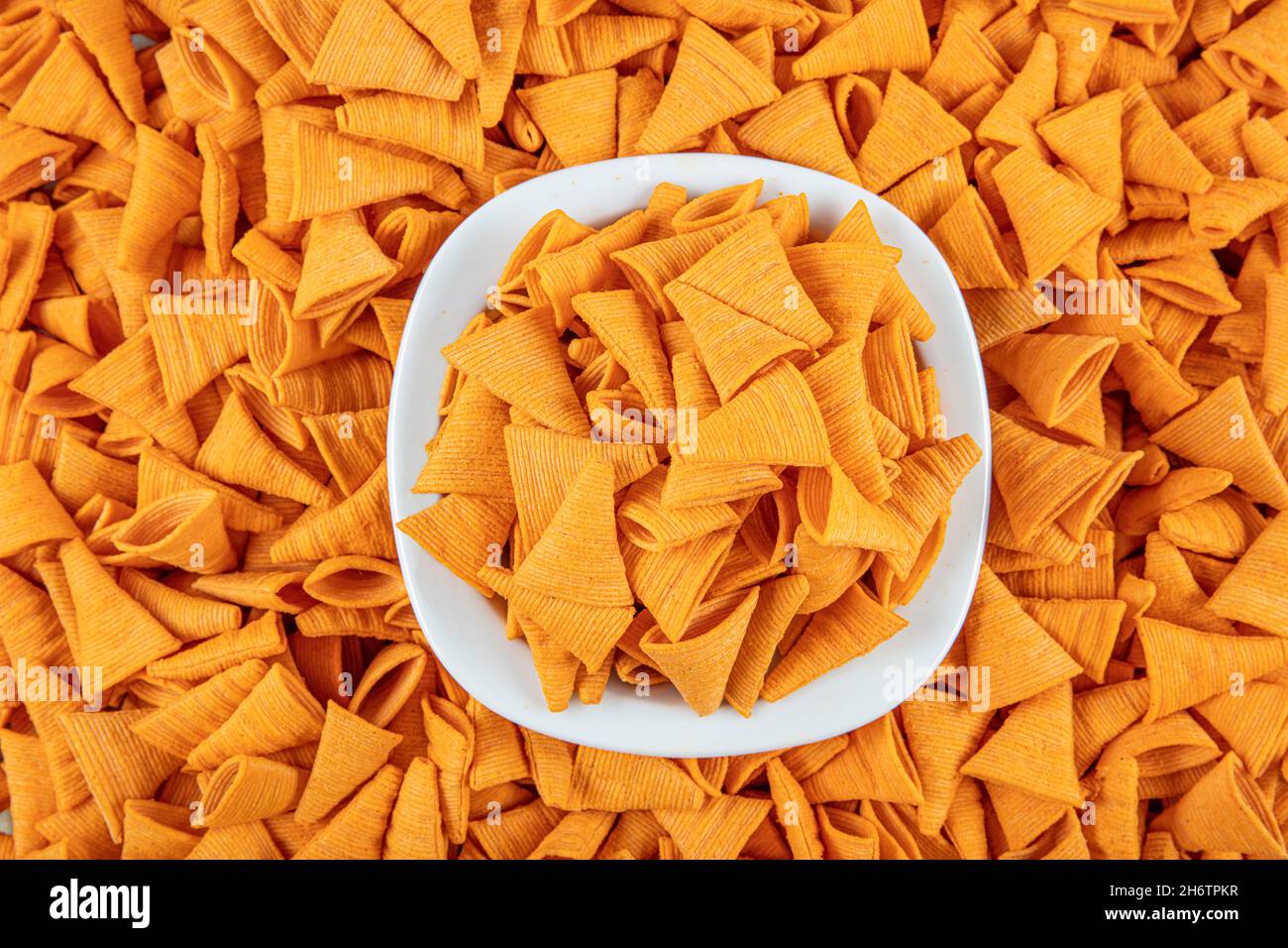Portion of cone shaped snack tornado shaped crackers. Yellow spicy