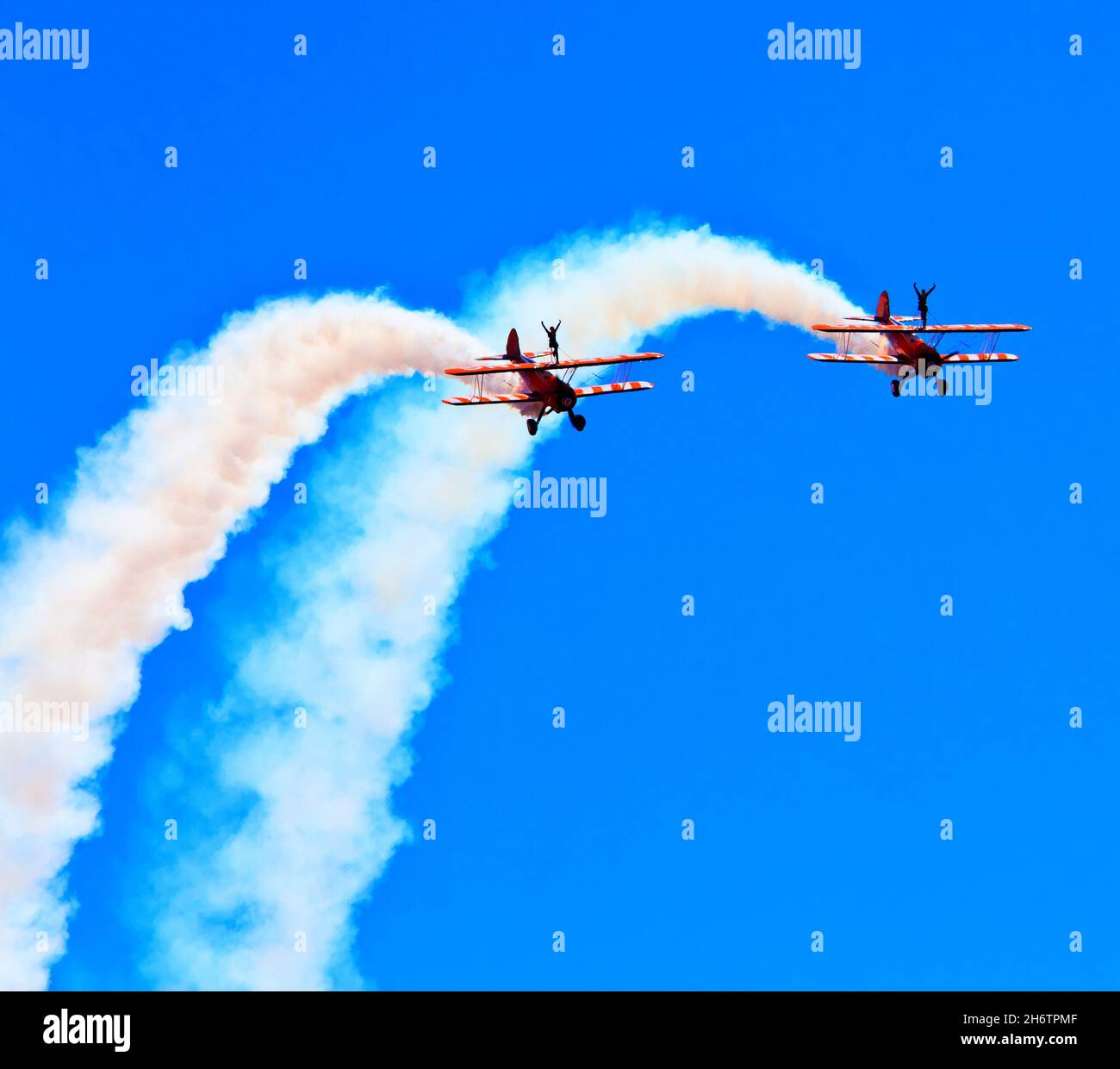 Wing walkers with two biplanes at airshow with blue sky and white smoke Stock Photo