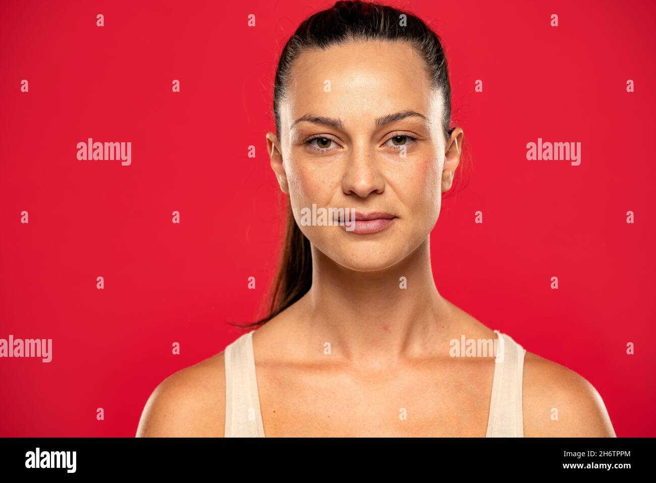 Portrait of beautiful serious woman with tied hair on a red background Stock Photo
