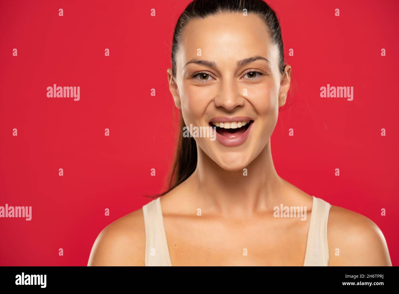 Portrait of beautiful smiling woman with tied hair on a red background Stock Photo