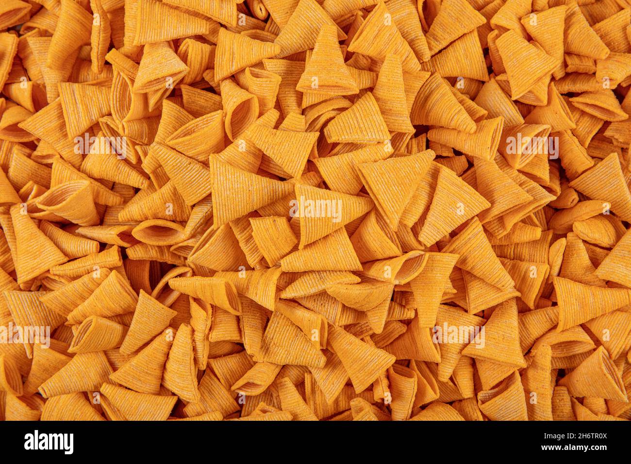 Portion of cone shaped snack tornado shaped crackers. Yellow spicy potato cone chips texture or Background of corn cone. Stock Photo