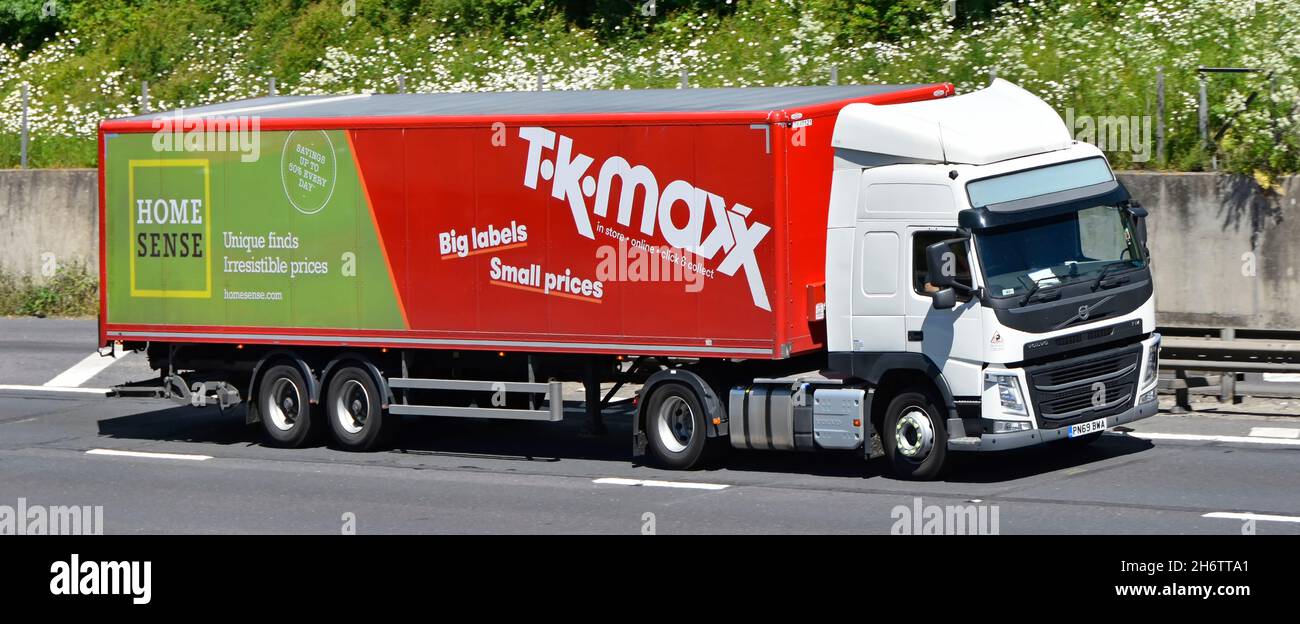 Multi business Home Sense & T K Maxx advertising on side of articulated supply chain trailer with white Volvo hgv lorry truck & driver on UK motorway Stock Photo