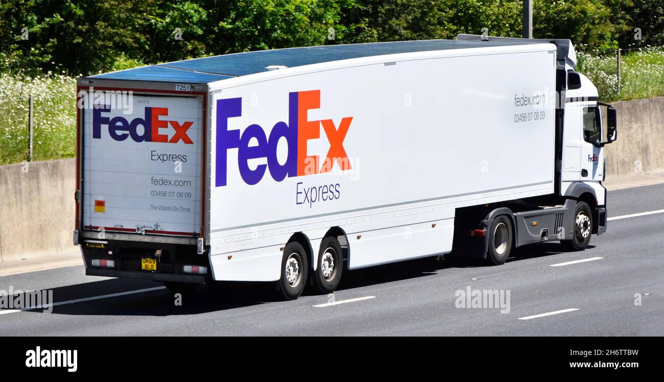 Side & back view of FedEx Express an American courier post & mail business brand with company logo on hgv lorry truck & trailer driving on UK motorway Stock Photo