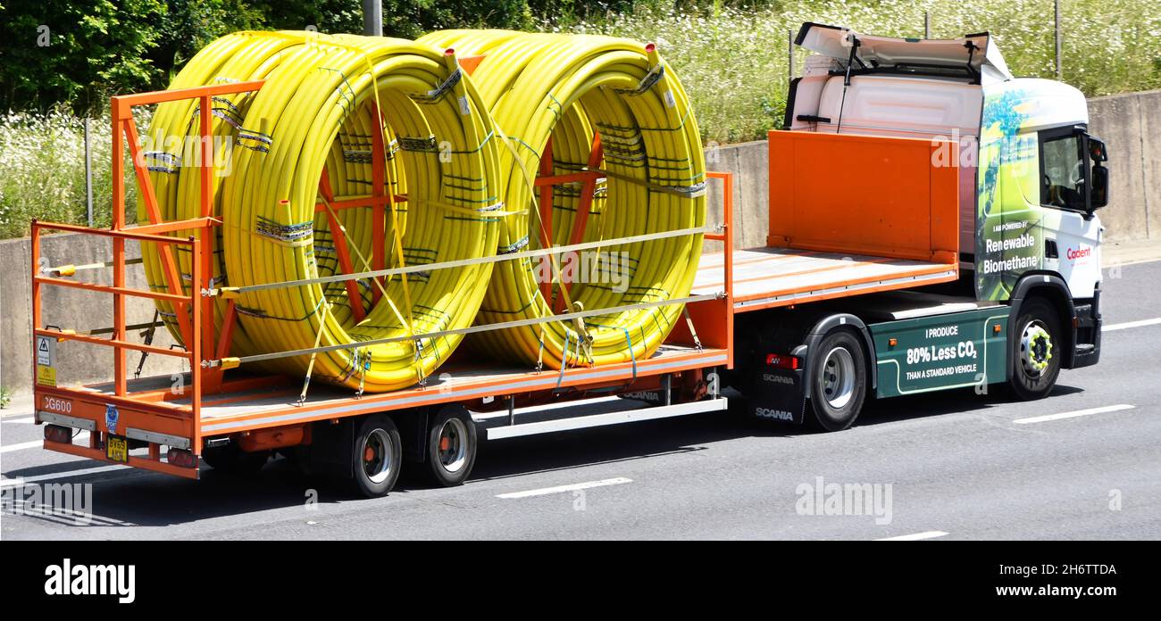 Cadent hgv lorry truck powered by Renewable Biomethane fuel reduces CO2 emissions trailer loaded with coils of flexible yellow gas main pipe tubing UK Stock Photo