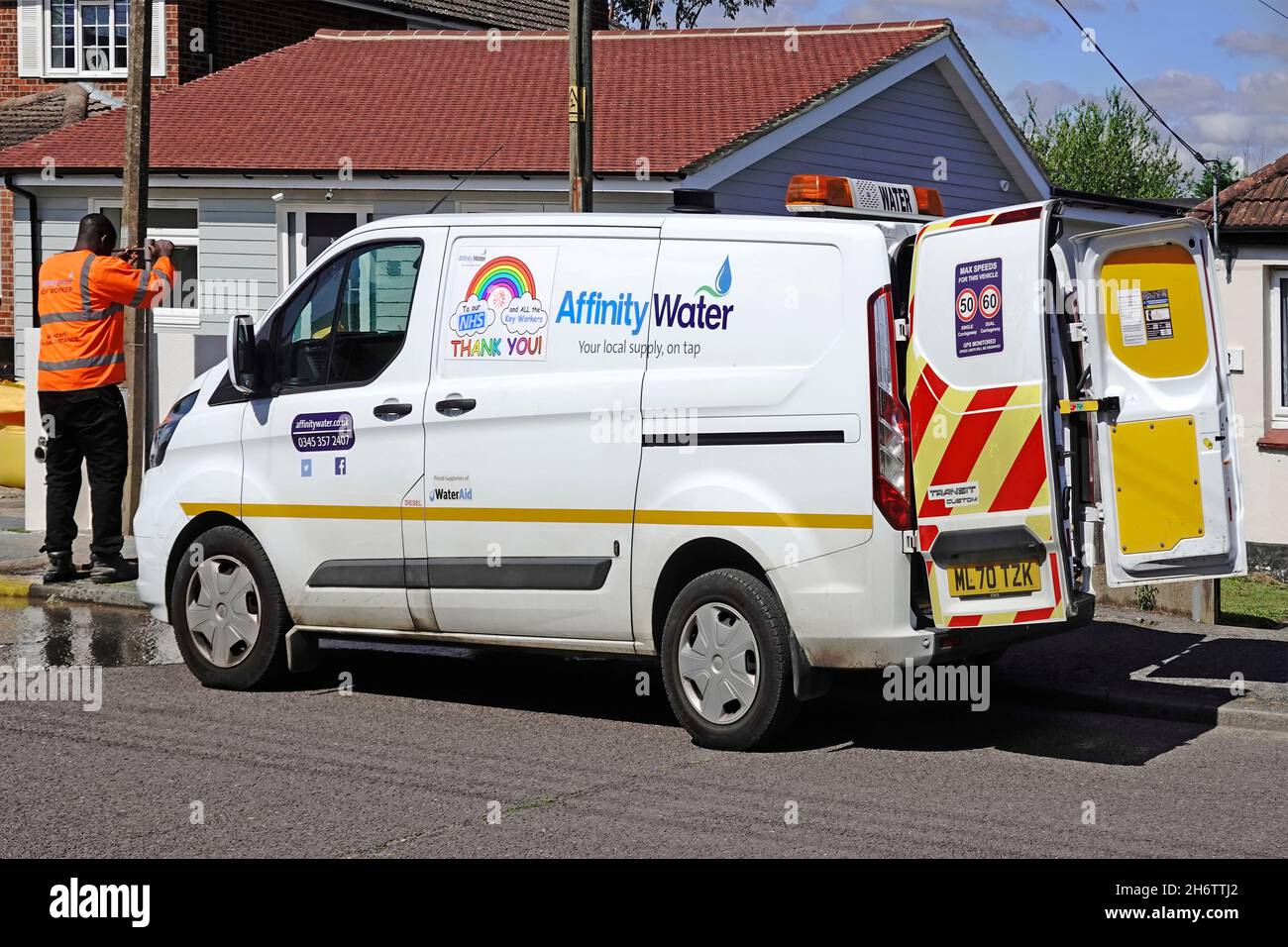 Side view & back doors open on Affinity Water board supply company business Ford van in road street man checks hydrants water flow in Essex England UK Stock Photo