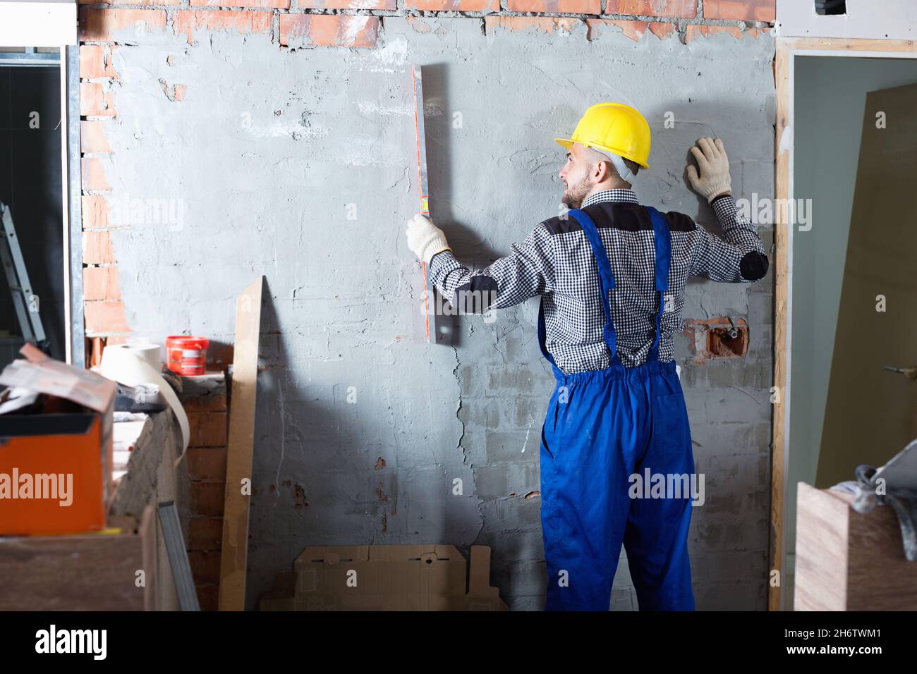 Builder Using Level Builder is working with level near the wall Stock Photo - Alamy
