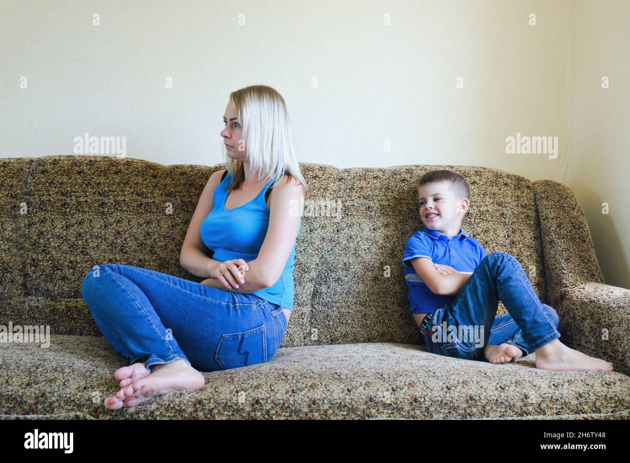 Mother and small child, boy at home sitting on couch, sofa and not talking. Unhappy family lifestyle, hobby and leisure. Stock Photo