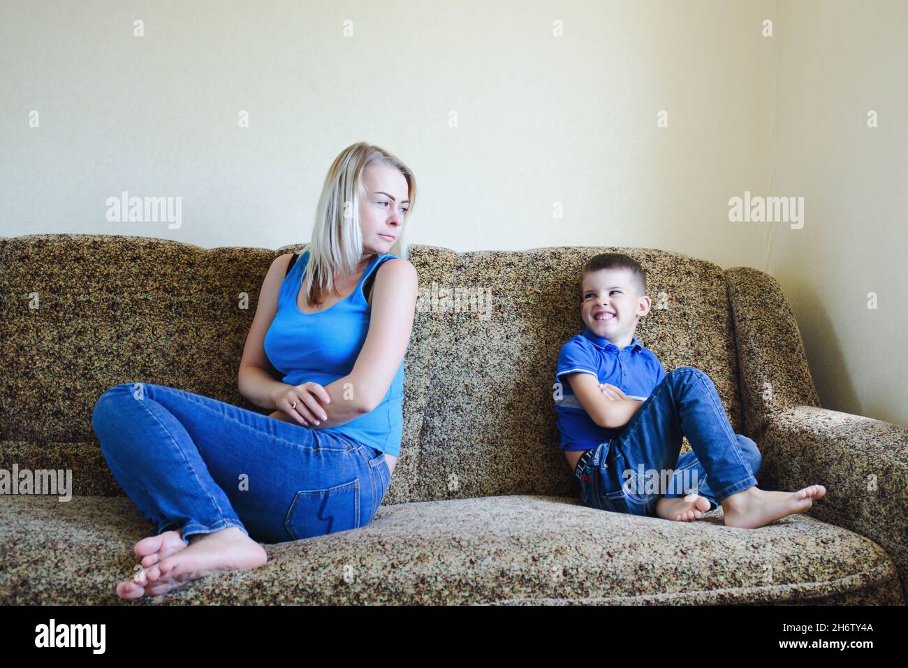 Mother and small child, boy at home sitting on couch, sofa and not talking. Unhappy family lifestyle, hobby and leisure. Stock Photo