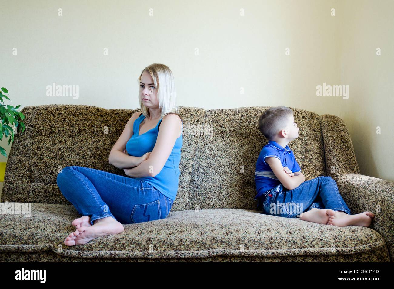 Mother and small child, boy at home sitting on couch, sofa and not talking. Unhappy family lifestyle, hobby and leisure. Stock Photo