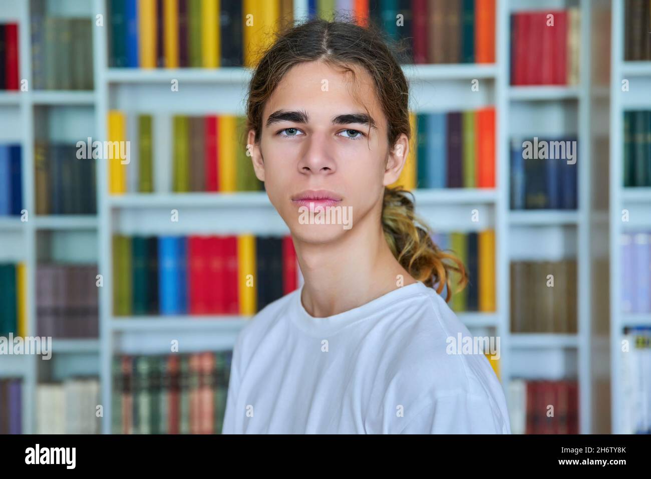 Portrait of a confident teenage boy looking at the camera in the library. Stock Photo