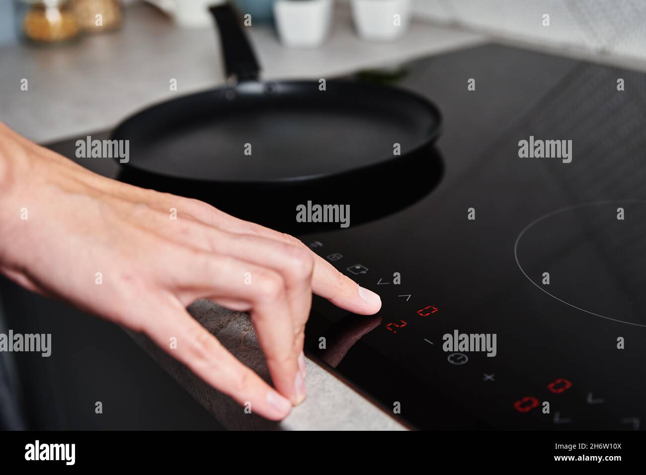 Modern kitchen appliance. Woman hand turn on induction stove to cook