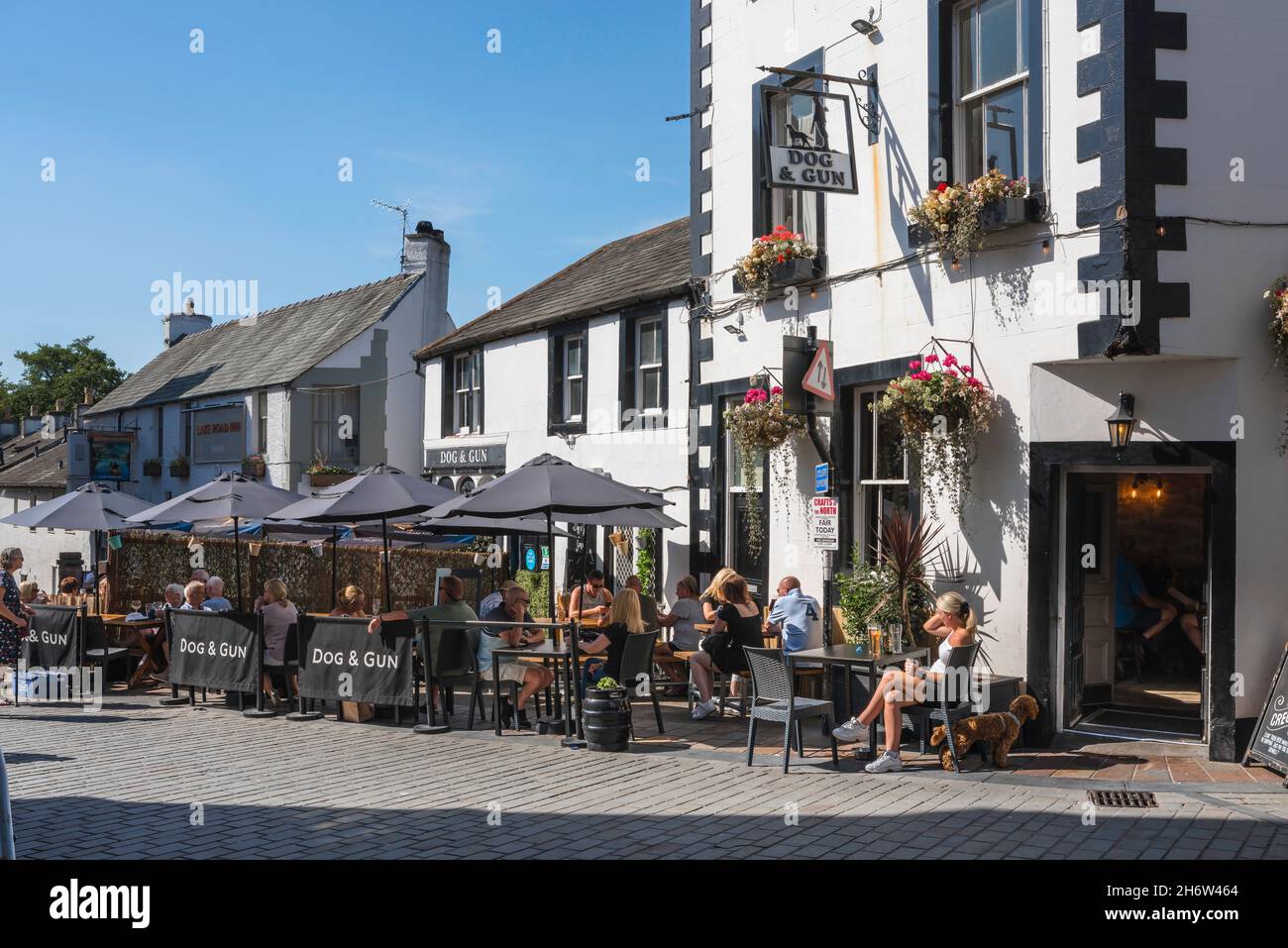 Pub UK, view in summer of people relaxing at tables outside the popular Dog And Gun pub in the centre of Keswick, Lake District, Cumbria, England, UK Stock Photo