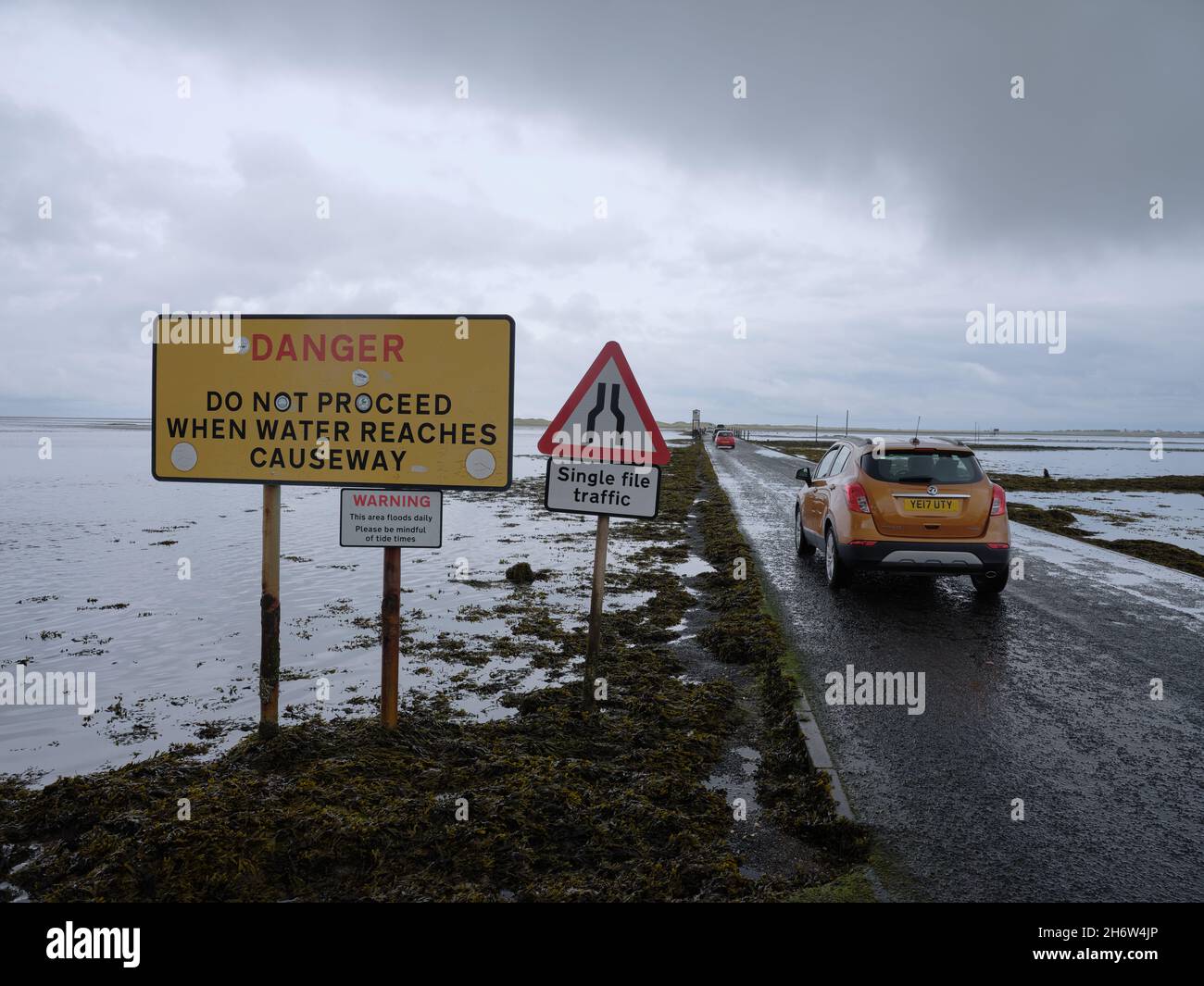 Cars crossing Lindisfarne Causeway a tidal causeway linking the historic Holy Island of Lindisfarne with the mainland of Northumberland England UK Stock Photo