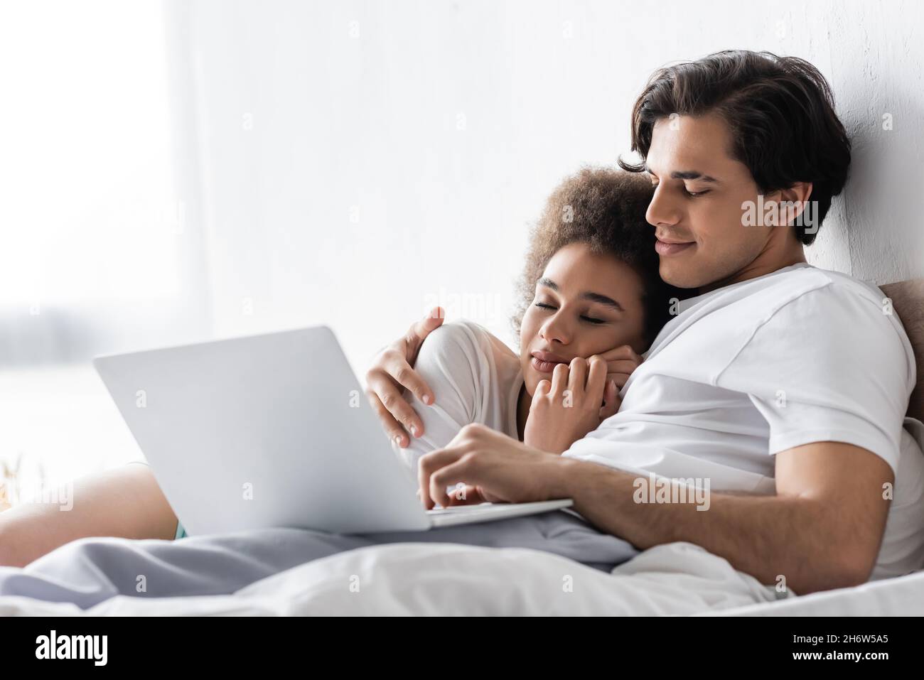 african american woman sleeping on chest of boyfriend with laptop Stock