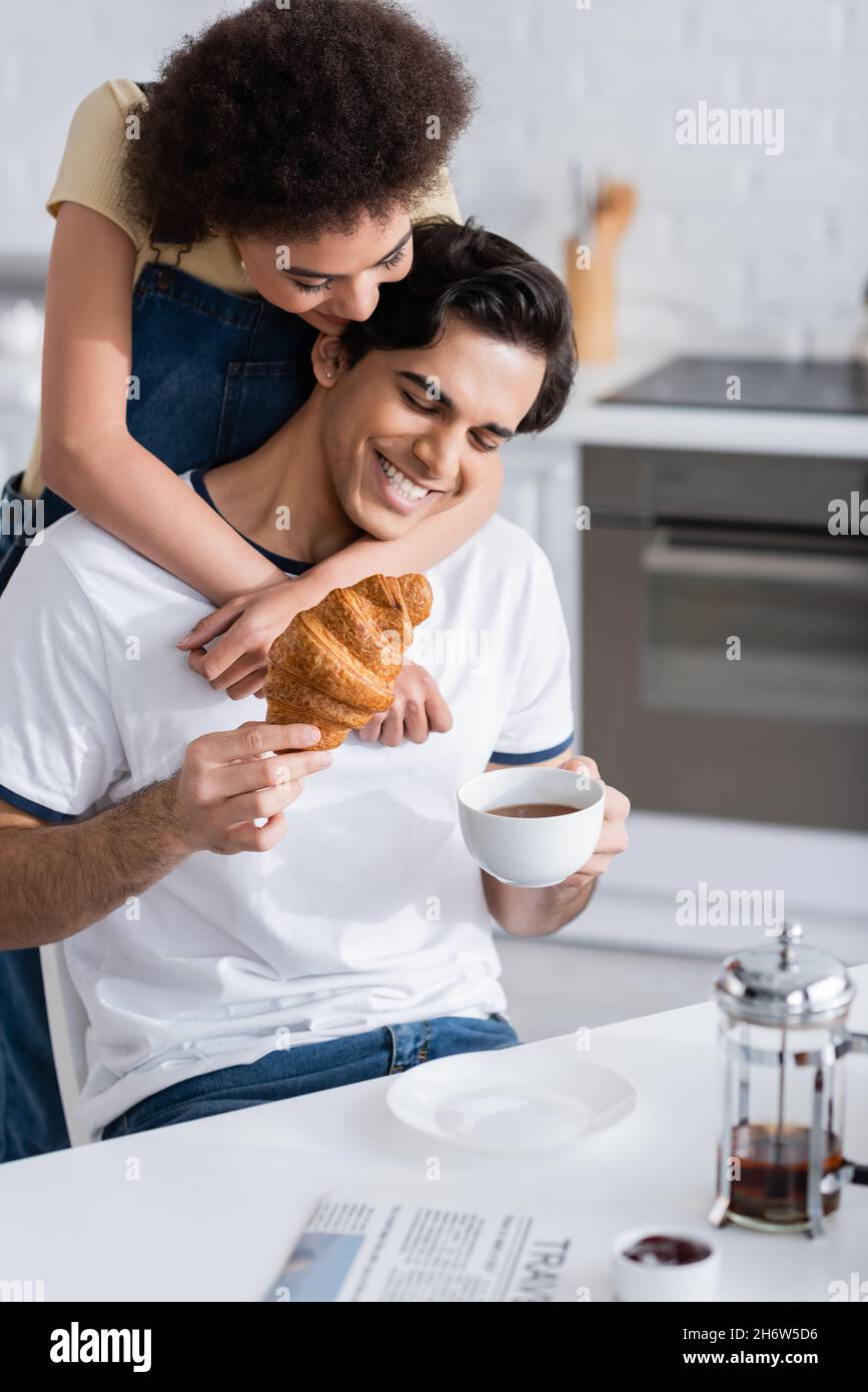 happy african american woman hugging boyfriend with cup of tea and ...
