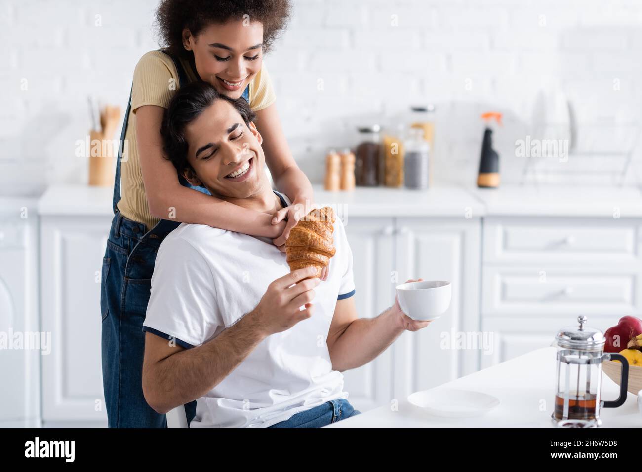 happy african american woman hugging boyfriend with cup of tea and ...